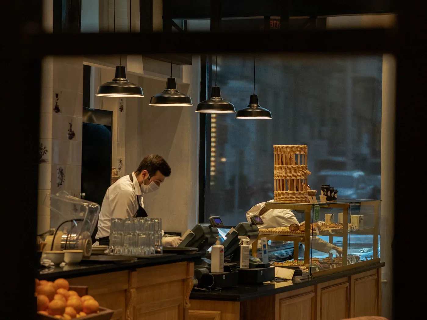 Interior cálido de una panadería, con el mostrador y un empleado trabajando.